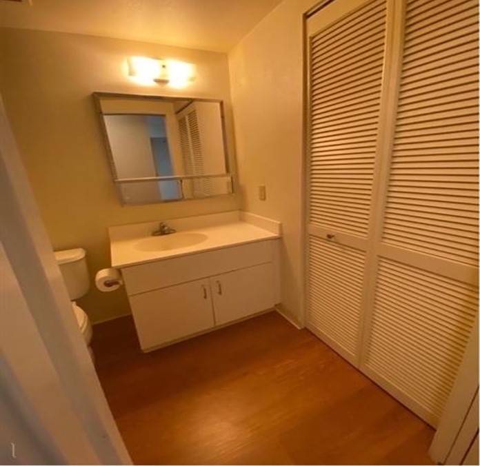 A bathroom with a white cabinet and a mirror above it.